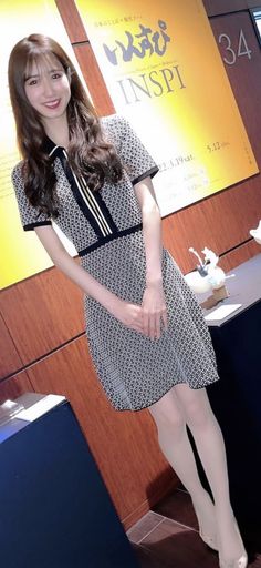 Woman in a patterned dress and white tights standing indoors