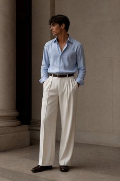 Man in a light blue shirt and white pants standing outdoors