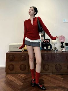 Woman in a red cardigan and mini skirt winking indoors