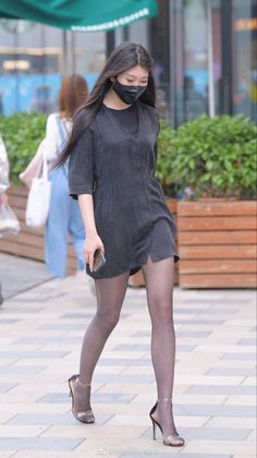 Woman in a black dress and mask walking on a street