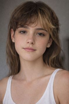 Young woman with long hair and freckles wearing a white tank top