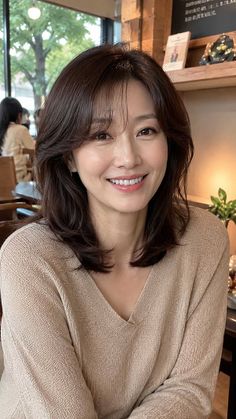 Woman with short brown hair and a v-neck sweater smiling indoors