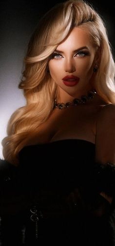 Woman with blonde hair and red lipstick wearing a strapless top and necklace