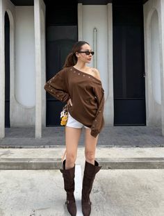 Woman in an off-shoulder top, white shorts, and knee-high boots outdoors