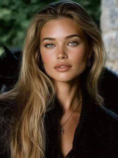 Woman with long blonde hair and blue eyes wearing a necklace and earrings