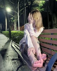 Woman with blonde hair and plaid skirt sitting on a park bench at night
