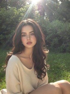 Woman with long dark hair and freckles sitting outdoors in soft sunlight
