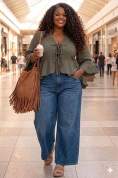 Woman with long curly hair in a shopping mall, holding a drink and smiling