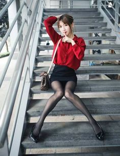 Woman in a red shirt and black skirt sitting on outdoor stairs