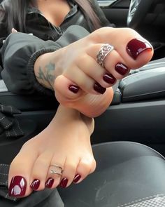 Woman's feet with red nail polish and toe rings inside a car