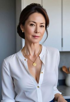 Woman in a white blouse with gold jewelry and an updo hairstyle indoors