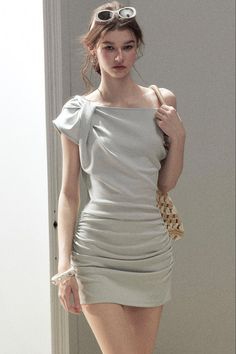Woman in a light grey ruched mini dress with sunglasses on her head