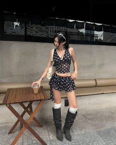 Woman in a polka dot top and mini skirt with long boots outdoors
