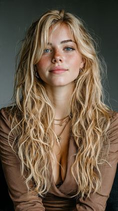 Woman with long blonde hair and freckles wearing a brown top with cleavage