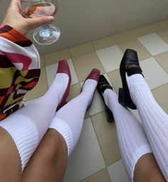 Two people wearing white socks and different shoes on a tiled floor