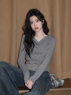 Woman with long black hair wearing a gray top and wide leg jeans