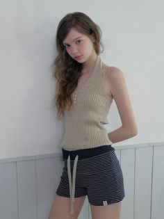 Woman with long hair wearing a halter top and striped shorts indoors
