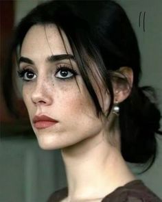 Woman with dark hair and freckles wearing pearl earrings and smokey eye makeup