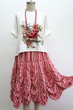 Mannequin wearing an embroidered white shirt and a striped pink skirt with a statement necklace