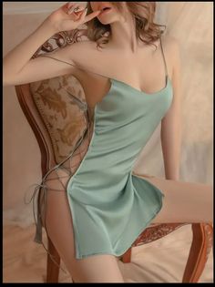 Woman in a light green satin slip dress with lace-up sides, posing indoors