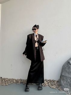 Woman in an oversized blazer, bra top, and long skirt posing outdoors