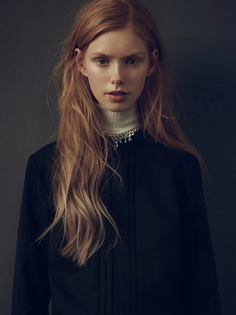 Woman with long blonde hair wearing a white turtleneck and black top