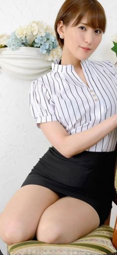 Woman with short hair wearing a striped shirt and black skirt, sitting indoors