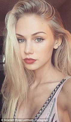 Blonde woman with blue eyes and pink top looking at the camera