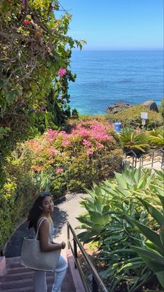 Woman walking up stairs with an ocean view and pink flowers