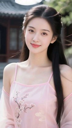 Woman with long dark hair wearing a pink dress with cherry blossom embroidery