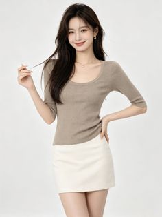 Woman with long dark hair wearing a brown top and white mini skirt
