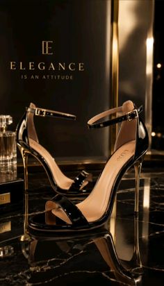 Pair of black patent leather high heels with gold stiletto heels on a reflective surface