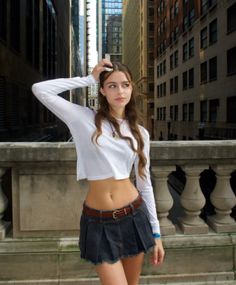Woman in a white crop top and denim skirt posing on a city street
