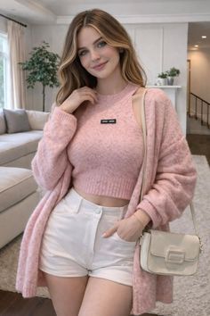 Woman in a pink cardigan and white shorts posing indoors