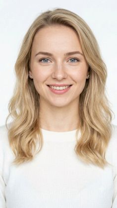 Blonde woman with blue eyes smiling in a white sweater