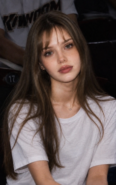 Young woman with long hair and bangs wearing a white t-shirt and heart necklace