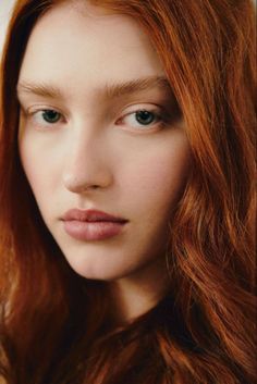 Close up portrait of a woman with long red hair and green eyes