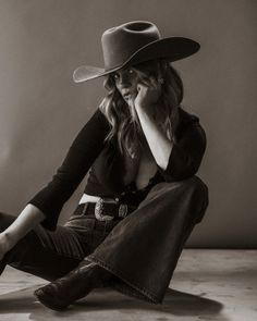 Woman in a cowboy hat, jeans, and boots posing in a studio