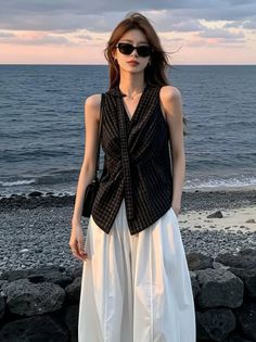Woman with long hair and sunglasses on a rocky beach at sunset