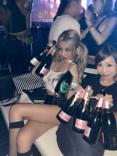 Two women holding champagne bottles in a dimly lit nightclub