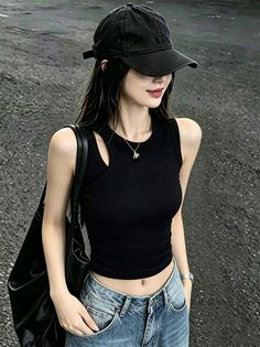 Woman in a black cap and tank top with blue jeans, showing her midriff