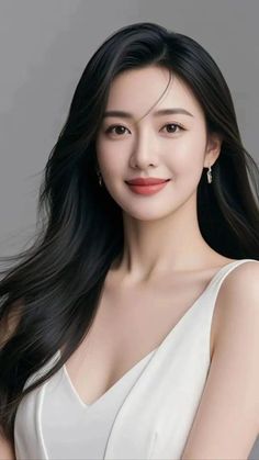 Woman with long black hair wearing a white top and earrings, smiling at the camera