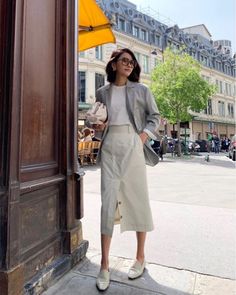 Woman in a blazer and midi skirt on a city street during the day