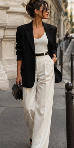 Woman in a black blazer and white pants walking on a street