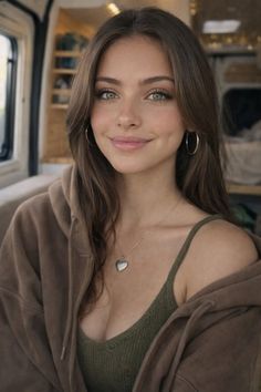 Woman with long brown hair and green eyes wearing a hoodie and heart necklace