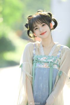 Woman in a traditional hanfu dress with buns in her hair, smiling outdoors