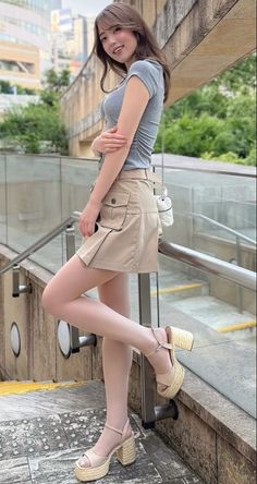 Woman in a gray top and mini skirt posing outdoors on a staircase
