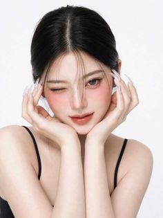 Woman with black hair and long nails winking with pink blush