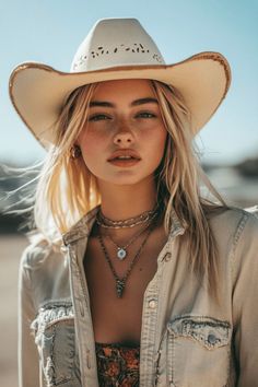 Woman with blonde hair and freckles wearing a cowboy hat and open denim shirt
