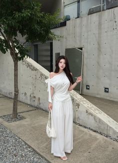 Woman in a white off-shoulder top and wide-leg pants standing outdoors
